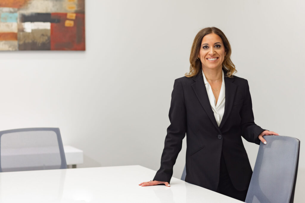 Woman in a suit standing by conference table.