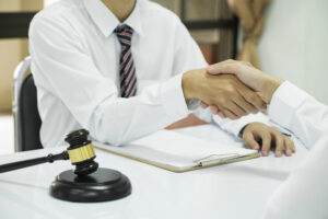 Business handshake with gavel and documents on table.
