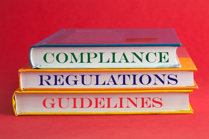 Stacked books labeled compliance, regulations, guidelines.