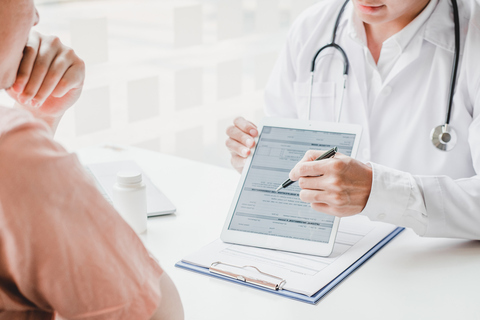 Doctor reviewing healthcare business AI use in medical form with patient on tablet