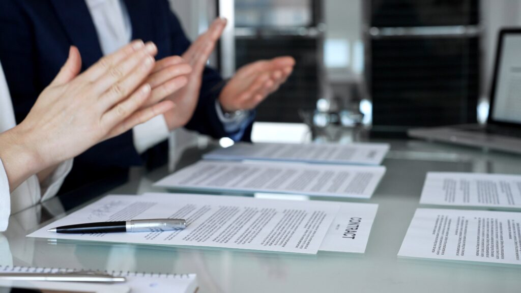 Business colleagues applauding over contract documents and pen